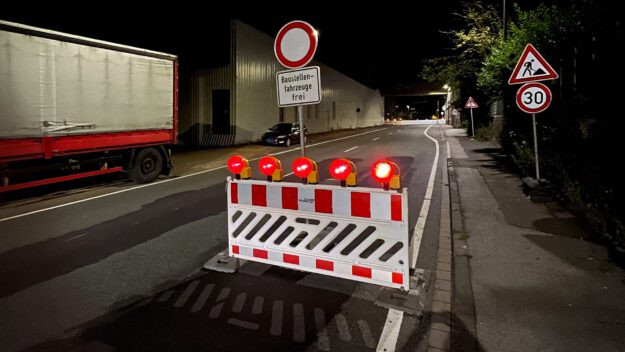 Foto: Carsten Menzel Auf einer nächtlichen Straße stehen rot-weiße Absperrbaken, rote Blinklichter und ein Schild "Durchfahrt verboten - Baustellenfahrzeuge frei"