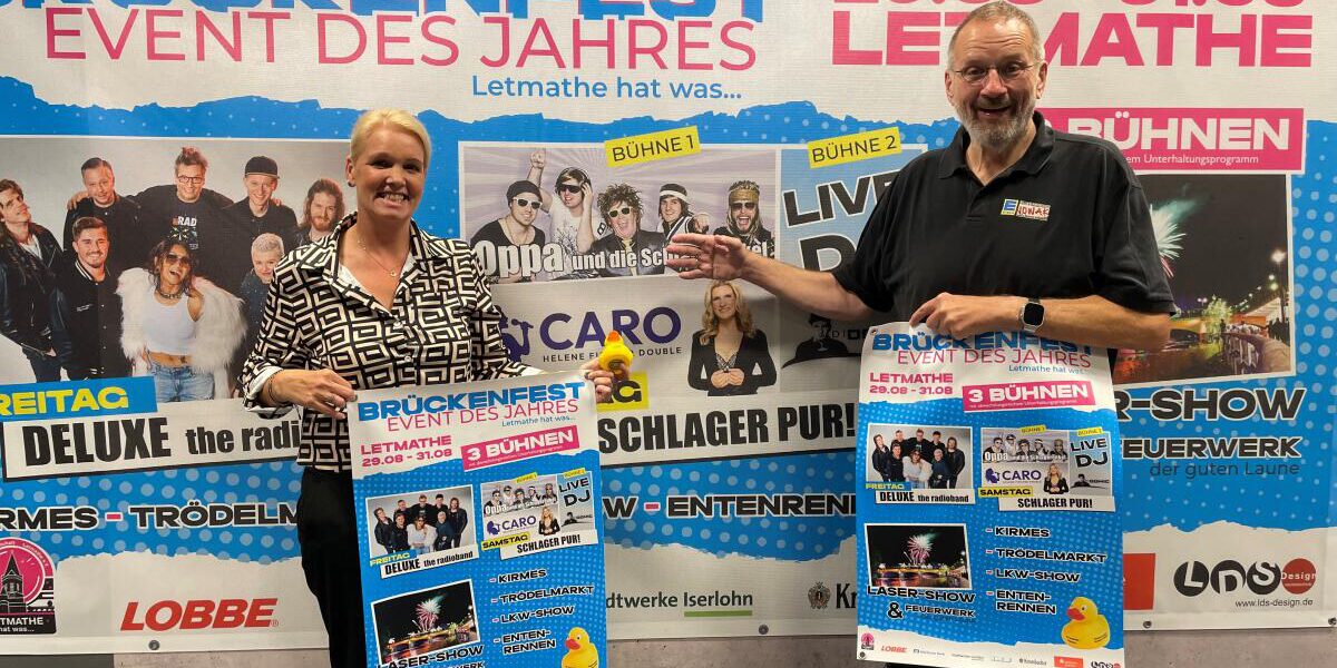 Sabrina Grigutsch und Paul Nowak halten Plakate für das Brückenfest hoch.