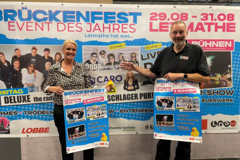Sabrina Grigutsch und Paul Nowak halten Plakate für das Brückenfest hoch.