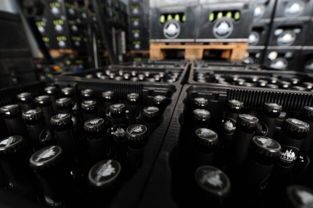 Foto: Michael May/Archiv Auf Paletten stehen aufgereiht schwarze, gefüllte Bierkästen.