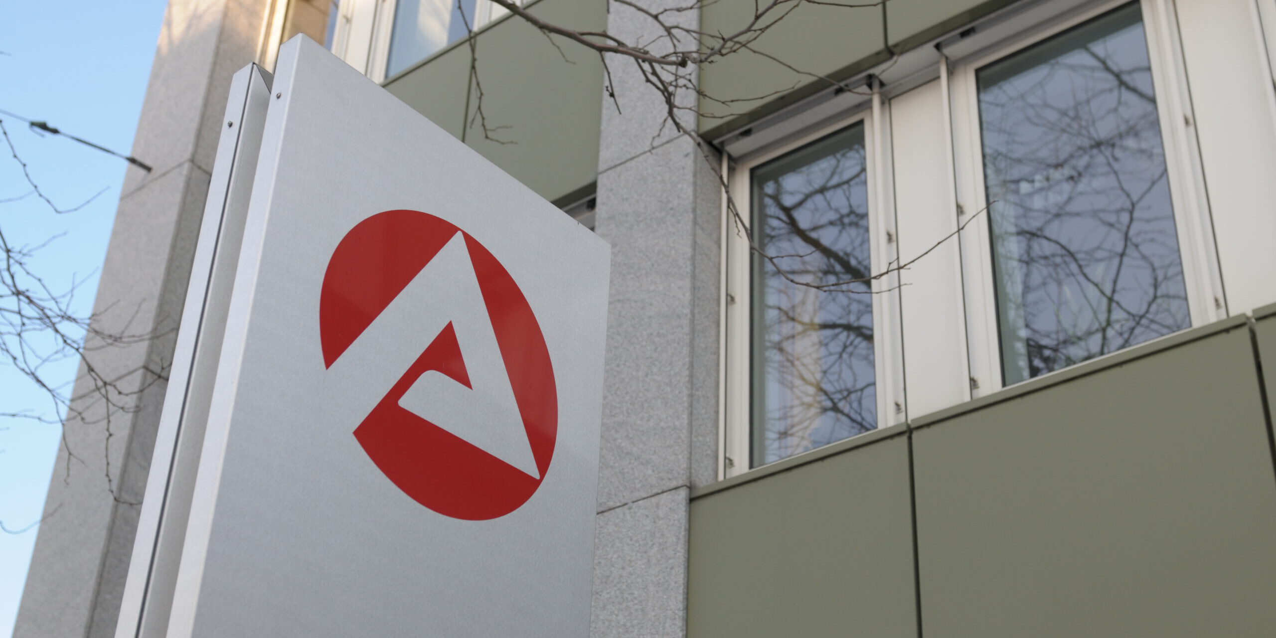 Das Logo der Agentur für Arbeit auf einer Säule vor einem Gebäude