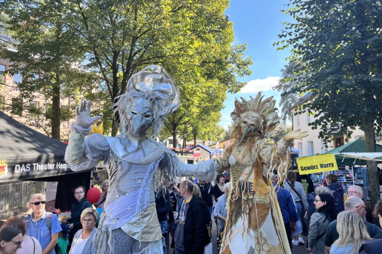 Zwei Stelzenläufer in venezianischen Karnevalskostümen in einer Menschenmenge