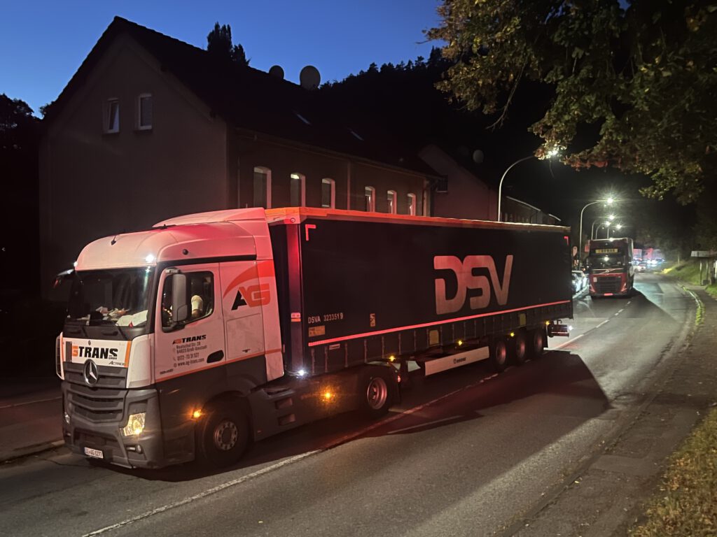 Mehrere Lkw stehen in der Dämmerung im Stau auf einer Bundesstraße.