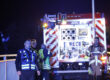 Feuerwehrleute stehen in der Nacht vor einem Feuerwehrwagen und lassen eine Drohne aufsteigen.