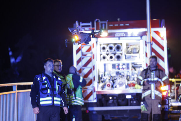 Foto: Dennis Echtermann Feuerwehrleute stehen in der Nacht vor einem Feuerwehrwagen und lassen eine Drohne aufsteigen.
