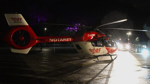 Foto: Carsten Menzel Ein rot-weißer Rettungshubschrauber der Luftrettung steht in der Dunkelheit auf einem Landeplatz auf einem Parkplatz.