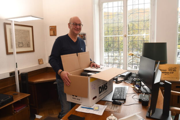 Foto: Carsten Menzel Ein Mann steht mit einem Umzugskarton an einem Behördenschreibtsich.