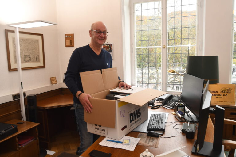 Foto: Carsten Menzel Ein Mann steht mit einem Umzugskarton an einem Behördenschreibtsich.