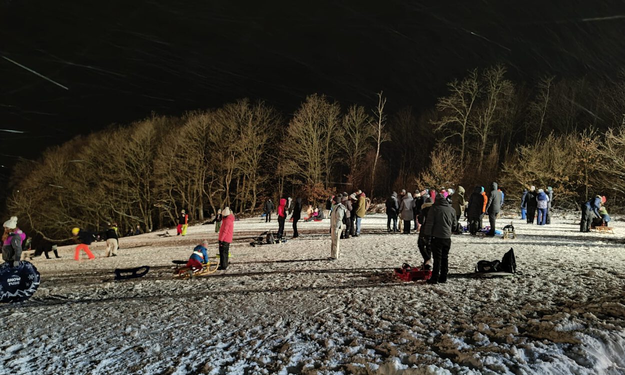 Menschen auf einer beleuchteten Schlittenwiese