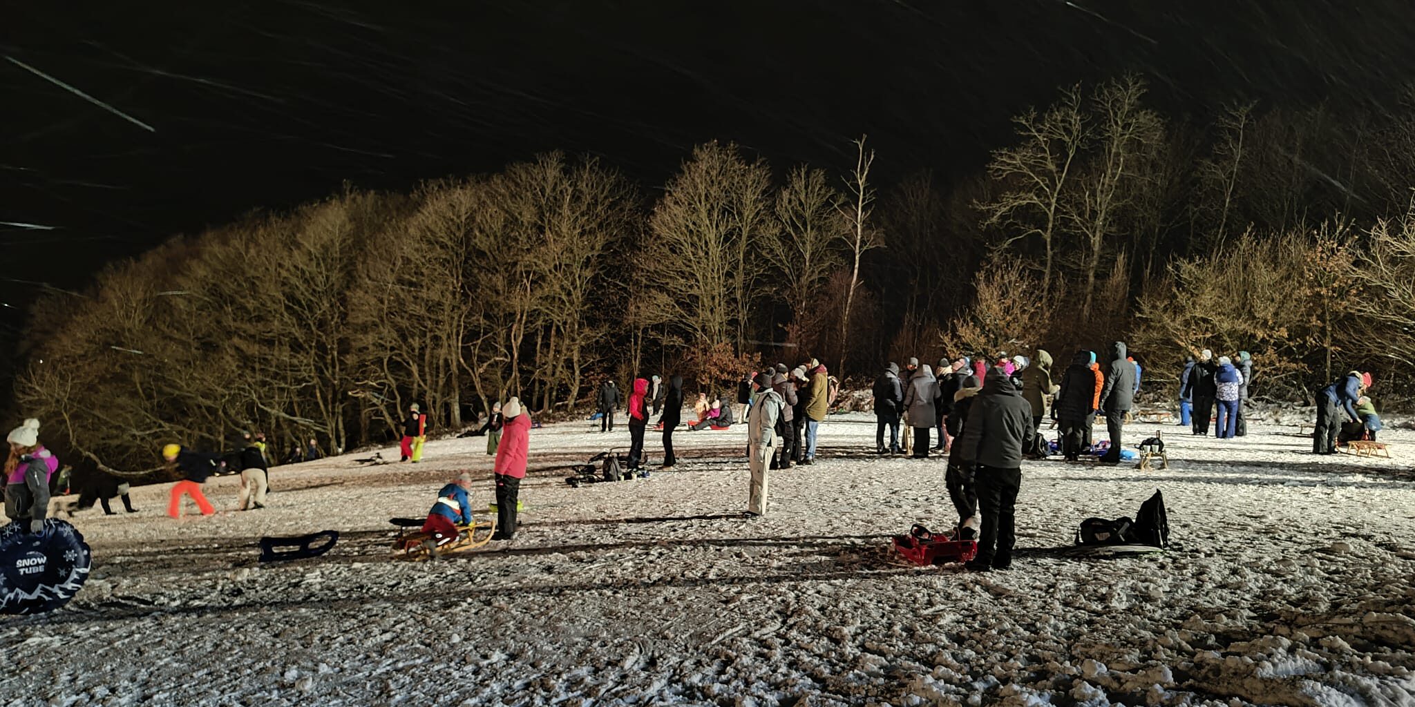Menschen auf einer beleuchteten Schlittenwiese