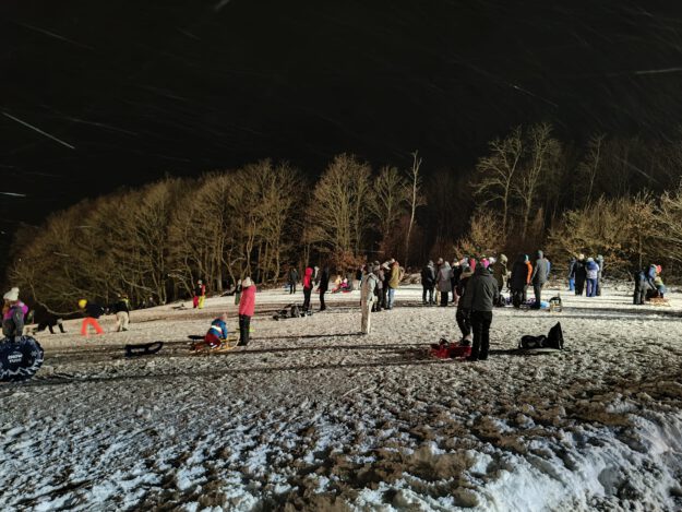 Menschen auf einer beleuchteten Schlittenwiese