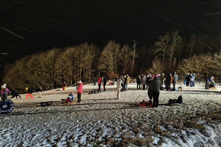 Menschen auf einer beleuchteten Schlittenwiese