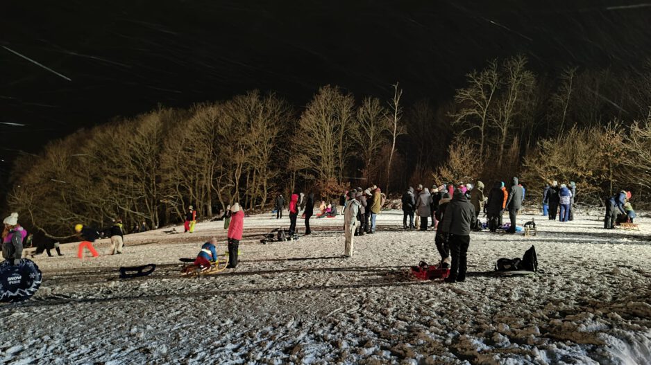 Menschen auf einer beleuchteten Schlittenwiese