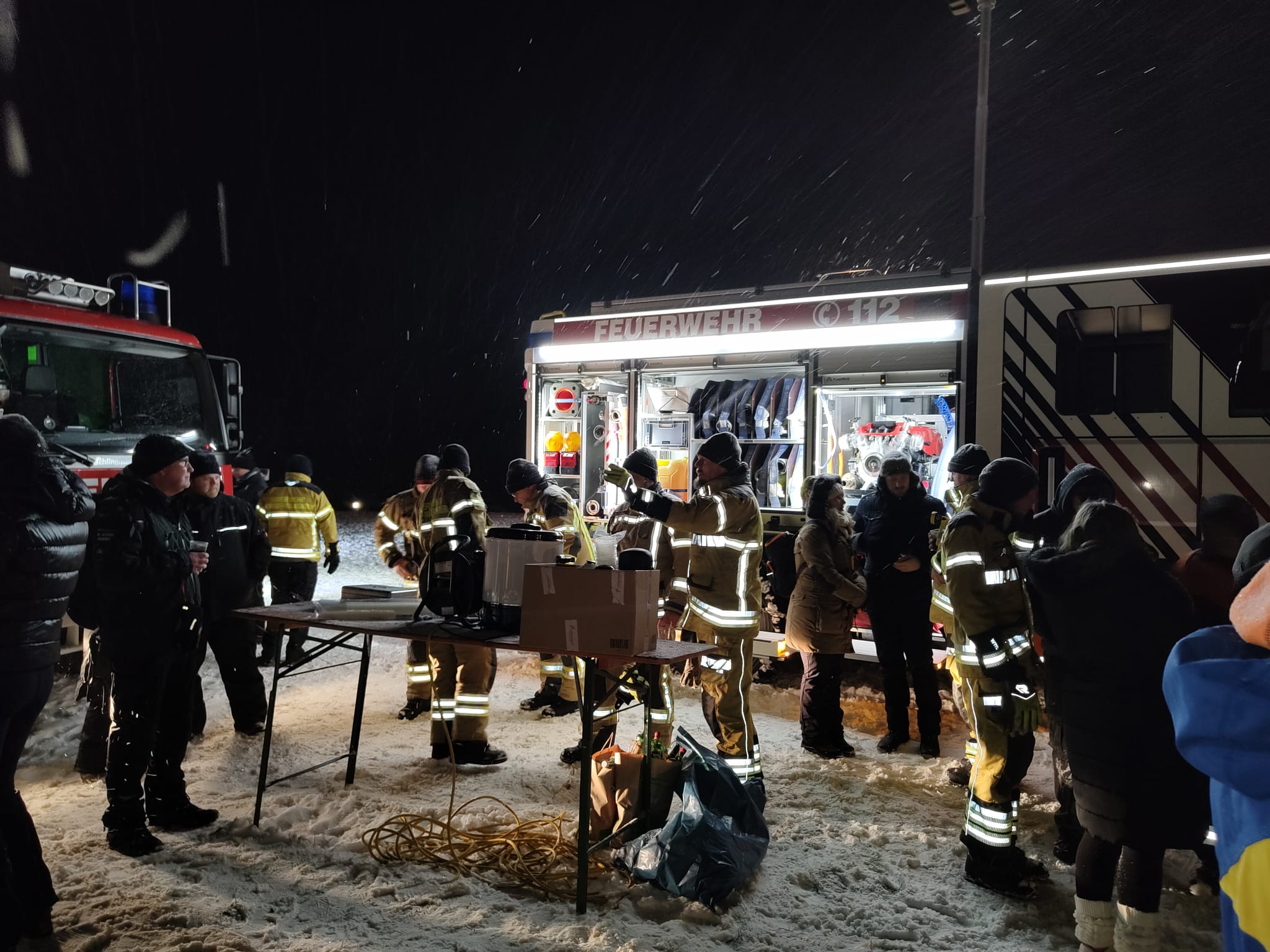 Menschen vor Einsatzfahrzeugen.