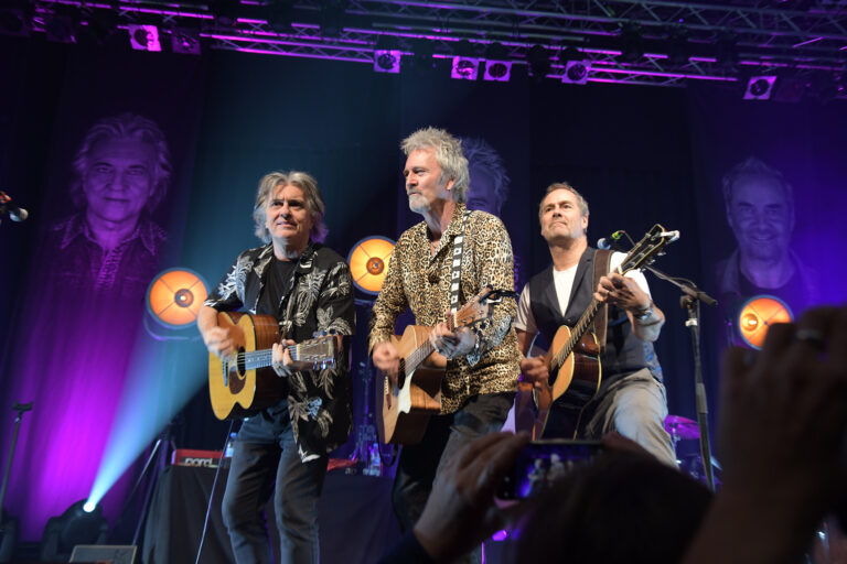 Drei Musiker mit Gitarren auf einer Bühne