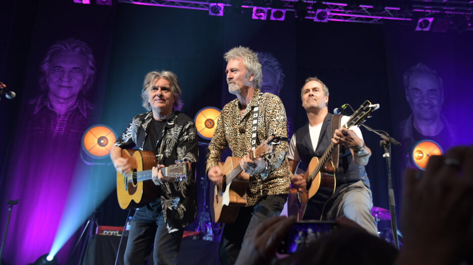 Drei Musiker mit Gitarren auf einer Bühne