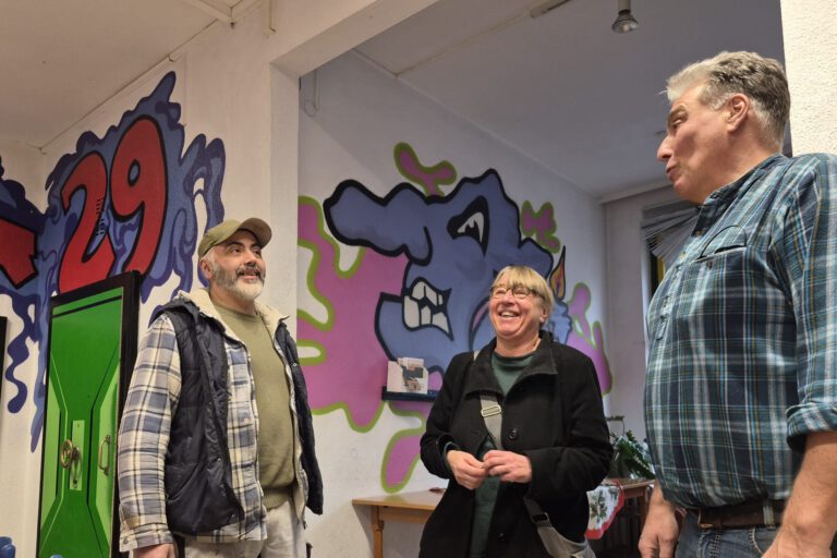 Zwei Männern und eine Frau in einem Raum mit Graffiti an den Wänden.