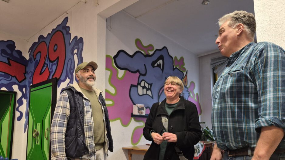 Zwei Männern und eine Frau in einem Raum mit Graffiti an den Wänden.