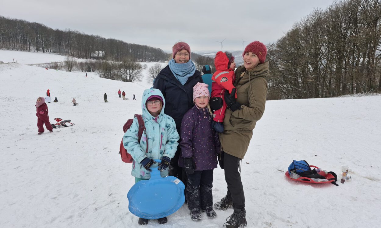Frauen mit Kindern auf einer verschneiten Wiese.