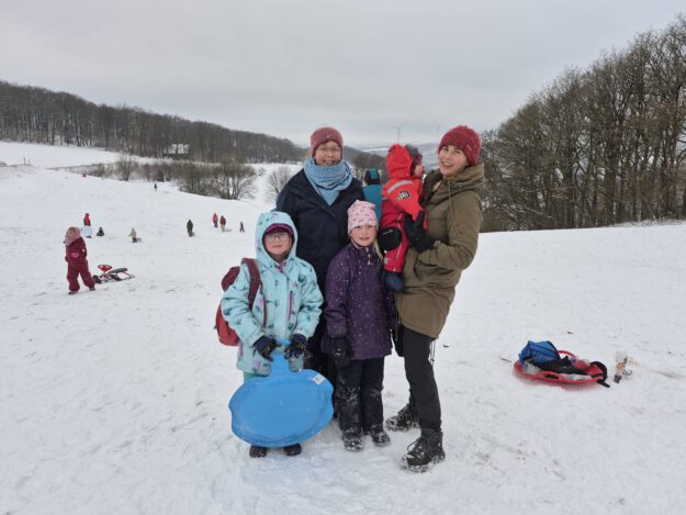 Frauen mit Kindern auf einer verschneiten Wiese.