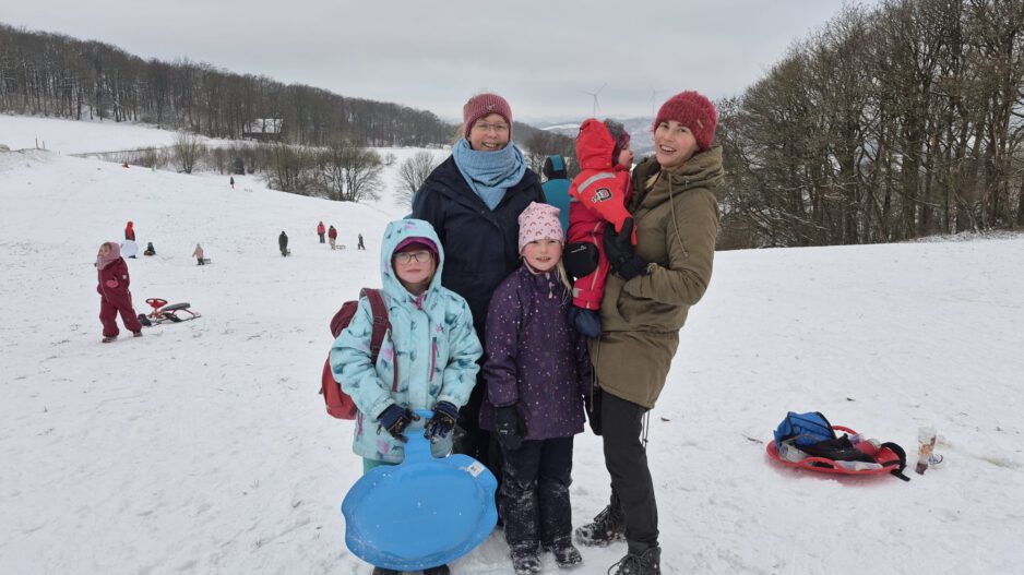 Frauen mit Kindern auf einer verschneiten Wiese.