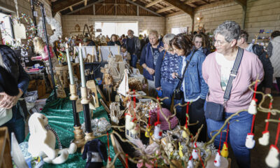 Besucherinnen und Besucher schauen sich in einer Scheune an Ständen mit handgemachter Deko, Holzarbeiten und Kunsthandwerk um.