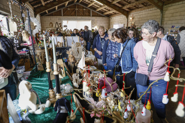 Besucherinnen und Besucher schauen sich in einer Scheune an Ständen mit handgemachter Deko, Holzarbeiten und Kunsthandwerk um.