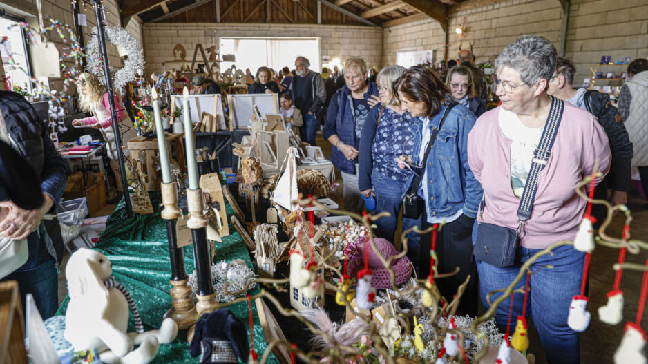 Besucherinnen und Besucher schauen sich in einer Scheune an Ständen mit handgemachter Deko, Holzarbeiten und Kunsthandwerk um.
