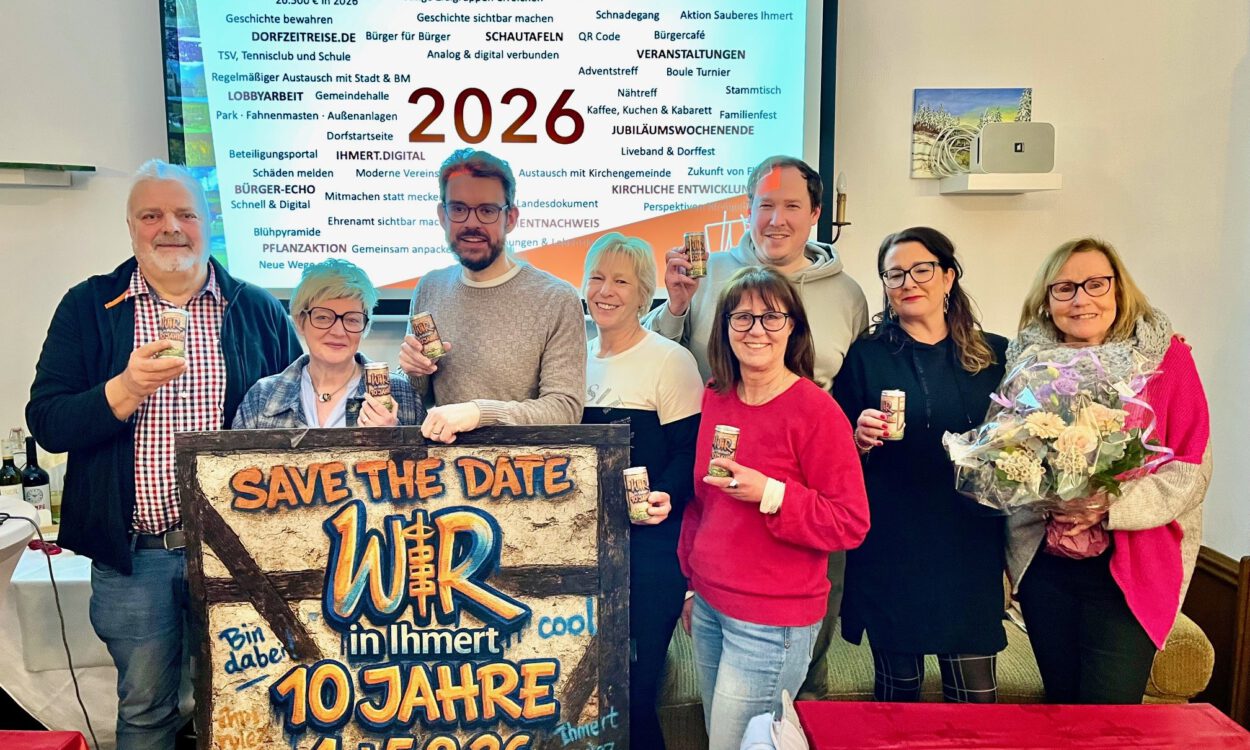Acht Personen stehen vor einer Präsentationsfolie mit der Jahreszahl 2026 und halten Getränkedosen; davor ein Schild mit „Save the Date – Wir in Ihmert, 10 Jahre“.