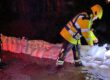 Einsatzkräfte legen nachts Sandsäcke aus, um eine überflutete Straße zu sichern.