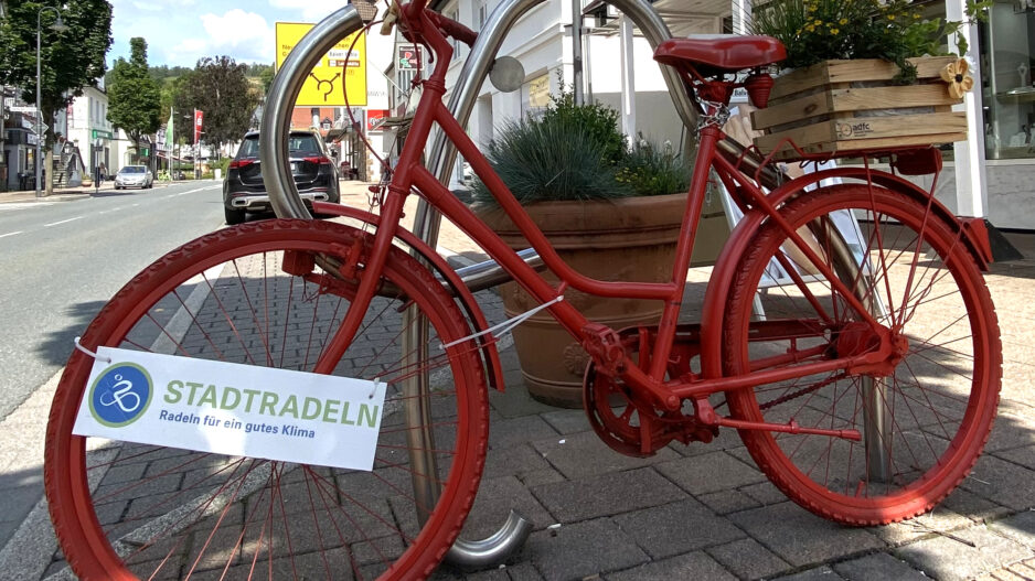 Ein rot lackiertes Fahrrad steht als Deko in der Innenstadt, am Rahmen hängt ein Schild mit der Aufschrift „Stadtradeln – Radeln für ein gutes Klima“.