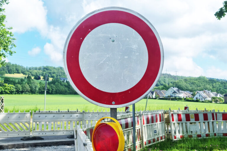 Foto: Hannah Heyn/Märkischer Kreis Ein rundes Verkehrsschild „Durchfahrt verboten“ steht vor einer abgesperrten Straße mit Baustellenbarrieren in ländlicher Umgebung.