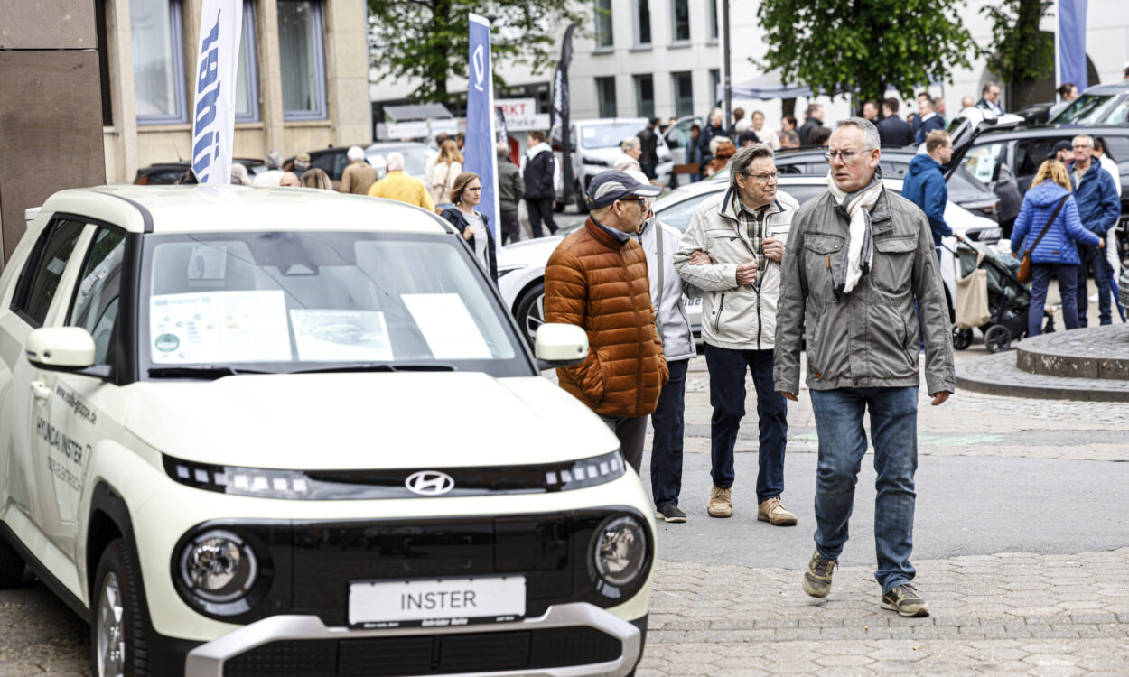 Menschen besuchen eine Autoschau in der Innenstadt und betrachten ausgestellte Fahrzeuge, im Vordergrund ein Hyundai-Modell.