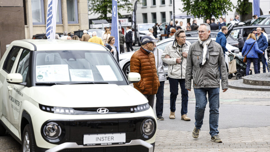Menschen besuchen eine Autoschau in der Innenstadt und betrachten ausgestellte Fahrzeuge, im Vordergrund ein Hyundai-Modell.