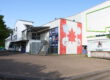 Außenansicht einer Eissporthalle mit Logos der Iserlohn Roosters und großem Ahornblatt an der Fassade.