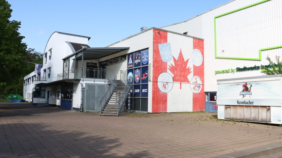Außenansicht einer Eissporthalle mit Logos der Iserlohn Roosters und großem Ahornblatt an der Fassade.
