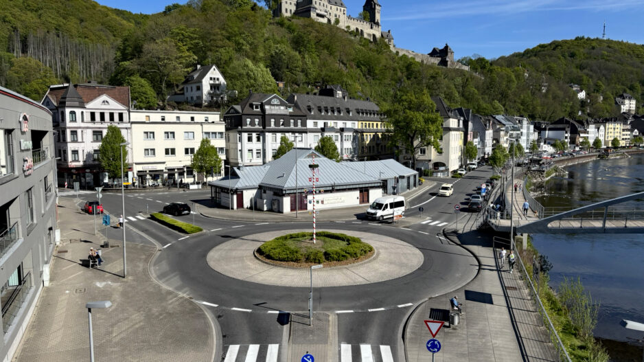 Blick auf den Kreisverkehr am Markaner, rechts fließt die Lenne und im Hintergrund sieht man die Burg Altena auf einem bewaldeten Hügel.