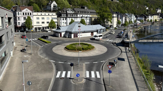 Blick auf den Kreisverkehr am Markaner, rechts fließt die Lenne und im Hintergrund sieht man die Burg Altena auf einem bewaldeten Hügel.