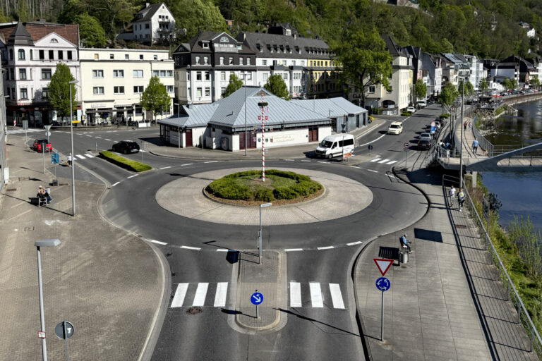 Blick auf den Kreisverkehr am Markaner, rechts fließt die Lenne und im Hintergrund sieht man die Burg Altena auf einem bewaldeten Hügel.