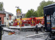 Aufbau eines Fahrgeschäfts auf einem Kirmesplatz: Arbeiter montieren das Karussell „VooDoo Jumper“ zwischen verstreuten Bauteilen und Fahrzeugen.