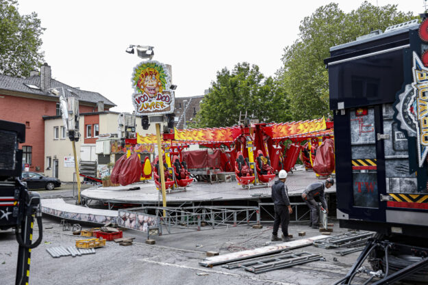 Foto: Lucas Sellmann Aufbau eines Fahrgeschäfts auf einem Kirmesplatz: Arbeiter montieren das Karussell „VooDoo Jumper“ zwischen verstreuten Bauteilen und Fahrzeugen.