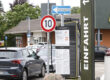 Hinweisschilder und geparkte Autos auf dem Parkplatz eines Schnellrestaurants. Im Vordergrund stehen ein Tempo-10-Schild, ein Einbahnstraßenschild sowie eine Informationstafel zur Parkdauerüberwachung. Rechts ist ein Teil des Restaurantgebäudes mit dem Schriftzug „Einfahrt“ zu sehen.