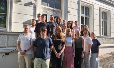 Eine Gruppe von Auszubildenden und ihren Begleitpersonen steht auf den Treppenstufen vor dem Eingang eines historischen Verwaltungsgebäudes für ein gemeinsames Gruppenfoto. Die jungen Erwachsenen sind in mehreren Reihen angeordnet und blicken in die Kamera. Die Aufnahme entstand bei sonnigem Wetter und vermittelt den Eindruck eines offiziellen Auftakts oder Begrüßungstermins zum Ausbildungsbeginn.
