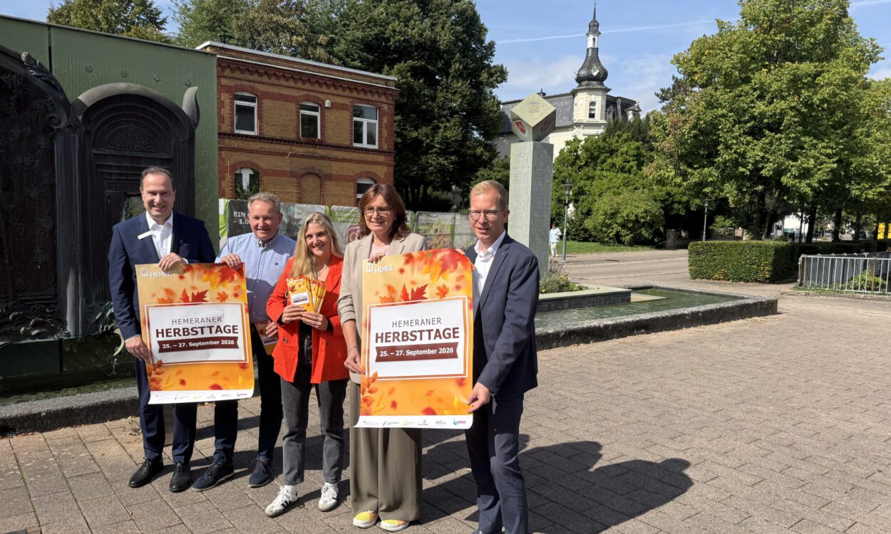 Fünf Personen präsentieren bei sonnigem Wetter vor einer Brunnenanlage in Hemer Plakate für die „Hemeraner Herbsttage“ vom 25. bis 27. September 2026.